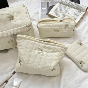 Detailed set of four quilted cream storage bags with delicate rabbit embroidery details