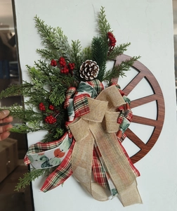 Christmas door wreath with wooden wheel, red berries, pine needles and a burlap bow