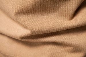 Macro shot showing soft camel knit fabric texture and fine stitch detail on men's polo