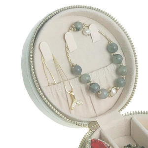 Detail view of round velvet jewelry box with necklace hooks and storage compartments