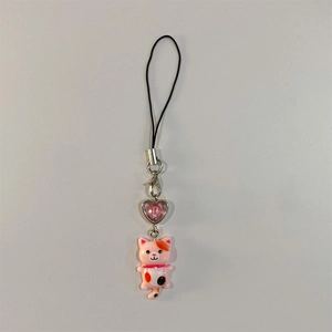 Detailed view of pink calico cat phone charm with a heart bead and black lanyard strap