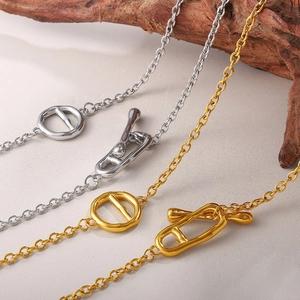 Minimalist stainless steel OT buckle necklace in gold and silver finish on wood