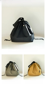 Detail of drawstring lunch bag with nylon fabric, side pocket, and metallic button snap