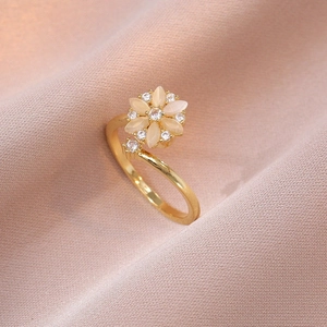 Dettaglio macro di un anello a fiore dorato con pietre preziose su tessuto rosa