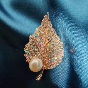 Elegant gold leaf brooch with colorful crystals and pearl on navy silk background