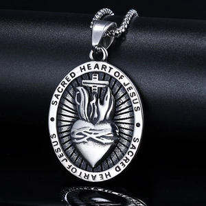 Macro shot of silver stainless steel Sacred Heart of Jesus cross pendant on black background