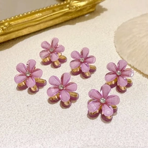 Close-up of six mini purple crystal flower hair claws with rhinestones on gold base