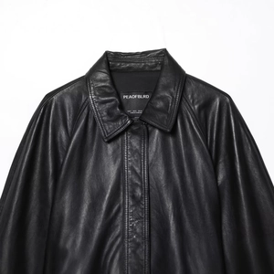 Gros plan du col d'une veste en cuir noir montrant la texture fine et les coutures détaillées