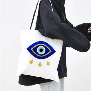 White canvas tote bag featuring blue Evil Eye print and gold teardrops for women