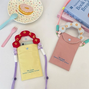 Close-up of vibrant pink and yellow mini canvas phone bags with woven embroidery handles