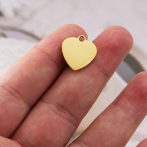 Pendentif cœur doré poli de 16x17mm présenté sur le bout des doigts pour bijoux DIY