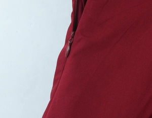 Détail d'une robe longue rouge montrant la fermeture éclair assortie et le tissu