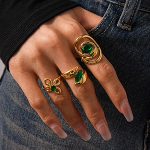 Detailed close-up of a three-piece gold ring set with green zircon stones on denim
