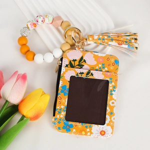 Detail of yellow floral card holder with silicone beaded bracelet and tassel charm