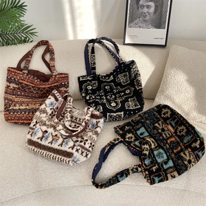 Flat lay of four vintage plush tote bags with varied ethnic patterns on a white sofa