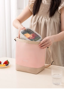 Detail of pink insulated lunch bag with shoulder strap holding a glass food container