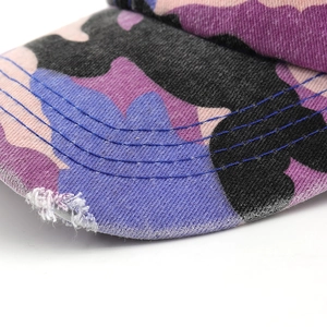 Macro shot of distressed camo baseball cap brim with colorful patterns and stitching