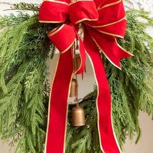 Detail of Christmas wreath with red gold-edged bow and bronze bells on green pine needles