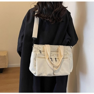 Close-up of cream corduroy bag on model featuring soft texture and wide shoulder strap