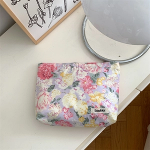Detailed view of floral cotton pouch with purple print and woven brand label on table
