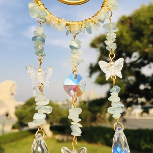 Detail of moon-shaped suncatcher with blue natural crystals and butterfly glass prisms
