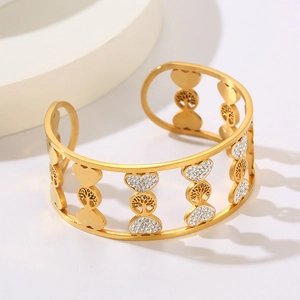 Golden Tree of Life and heart hollow cuff bracelet with white crystals on a white pedestal