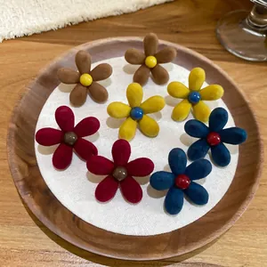 Set of eight velvet flower earrings in brown yellow burgundy and navy on wood tray