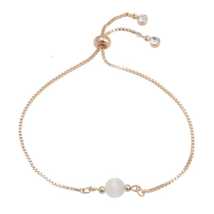 Detail of golden adjustable box chain bracelet with white bead and slider clasp