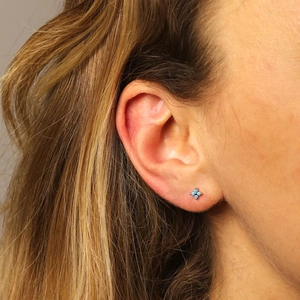 Detail of s925 silver stud earring with four blue stones in a clover shape on ear