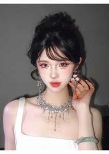 Detail of silver drop necklace and earrings set with sparkling crystals on model