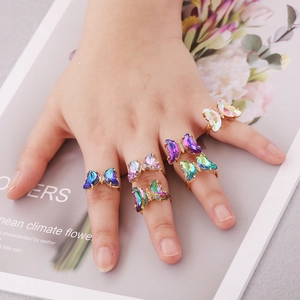 Detalle de un juego de 6 anillos de mariposa de cristal coloridos con acabado dorado