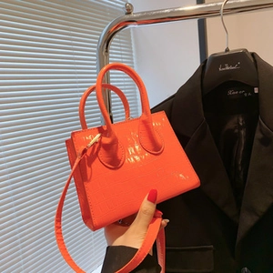 Close-up of orange faux crocodile leather mini handbag with top handles and strap