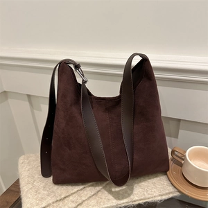 Vintage large dark brown suede hobo tote bag with wide leather strap on a soft knit blanket