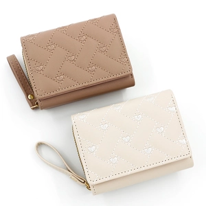 Close-up of woven texture with embroidered hearts on khaki and cream leather wallets