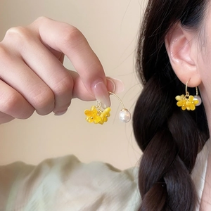 Detail of sweet osmanthus flower earrings with pearl drop on model's ear