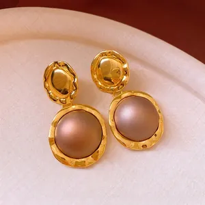 Vintage style round gold earrings with textured fold pattern and brown resin centers