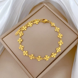 Golden titanium steel four-leaf clover chain bracelet on a white silk jewelry box background