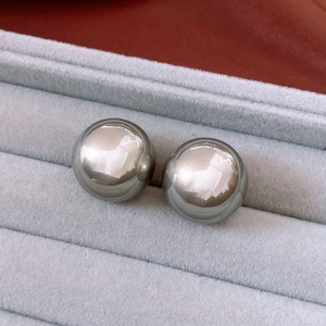 Macro shot of large polished dark grey metallic sphere earrings in a velvet jewelry box
