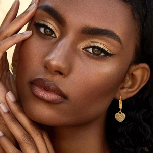 Gold plated heart pendant earrings with cubic zirconia stones worn by model