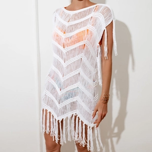 Detail of white crochet beach cover-up featuring wave knit pattern and long fringe trim