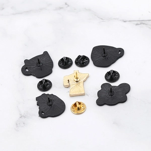 Enamel pin back set with gold and black butterfly clutches on marble surface