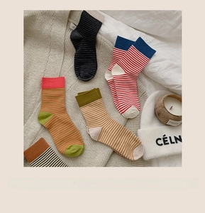Cinq paires de chaussettes en coton à rayures colorées présentées sur une literie douce