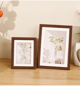 Detail of walnut wood frames with white matting and botanical prints on a wooden table