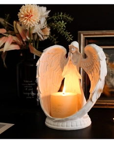 Macro detail of Nordic white praying angel candle holder with a glowing lit candle