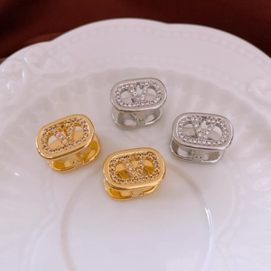 Detail of 18k gold and silver oval earrings with V-logo and micro-set cubic zirconia