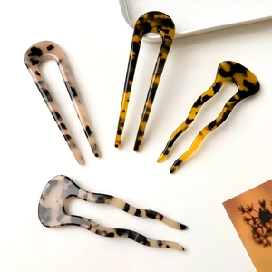 Detail of four tortoise shell acetate hair pins in U-shape and wavy designs