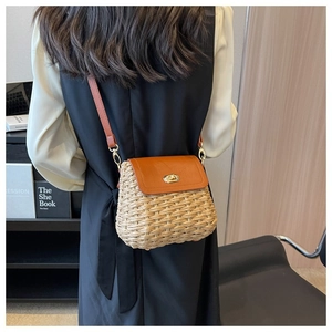 Detail of straw woven crossbody bag with brown leather flap and golden rotary lock