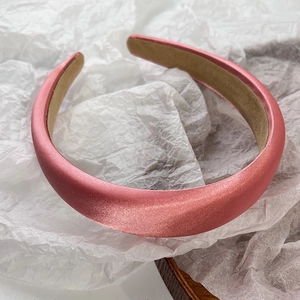 Top view of pink satin padded headband with premium texture on white background