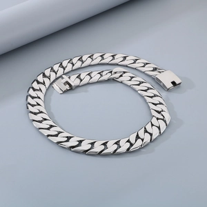 Detailed view of silver polished Cuban link chain with square box clasp on grey background