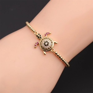 Detail of adjustable golden turtle bracelet with colorful zircon inlay on wrist